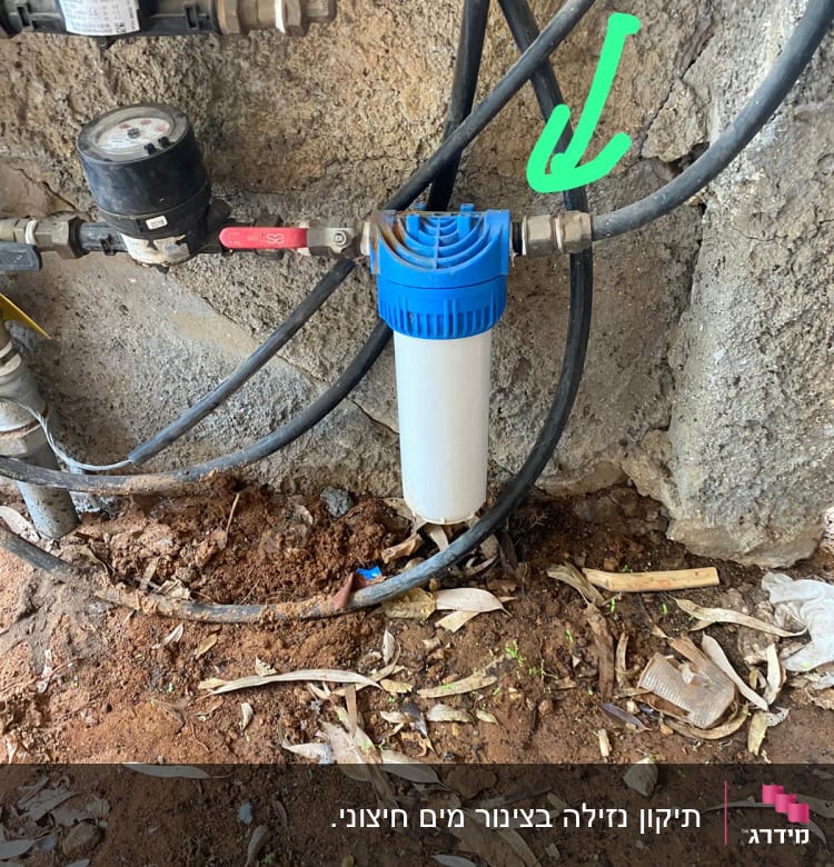 מסנן מים כחול מחובר לצינורות מתכת על קיר